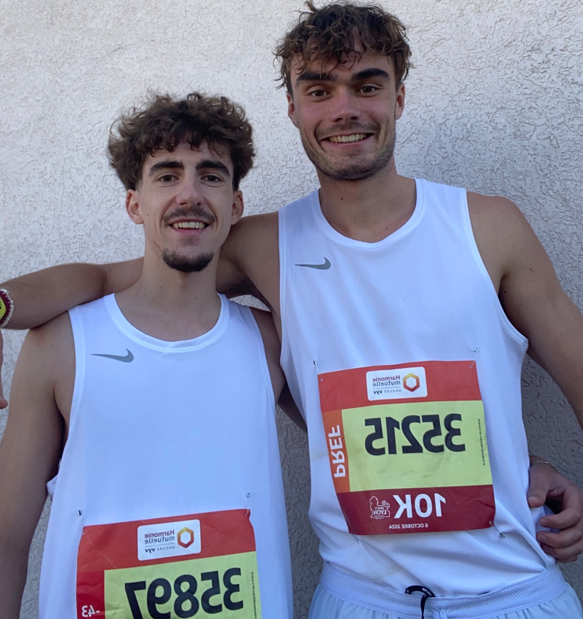 Deux athlètes souriants, côte à côte avec leurs dossards de course